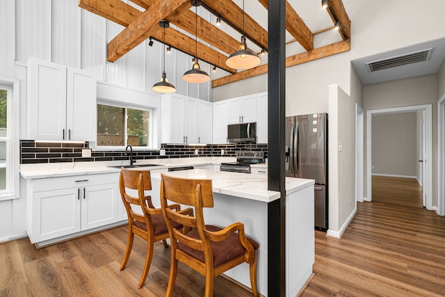 kitchen with wood finished floors, visible vents, decorative backsplash, and stainless steel appliances