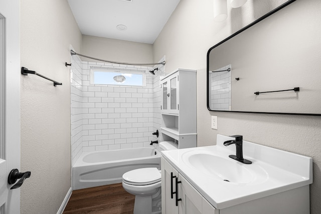 full bathroom with toilet, wood finished floors, washtub / shower combination, a textured wall, and vanity
