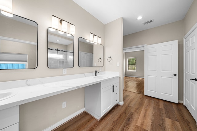bathroom with baseboards, wood finished floors, visible vents, and vanity