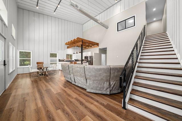 living area featuring a high ceiling, dark wood-style floors, track lighting, visible vents, and stairs