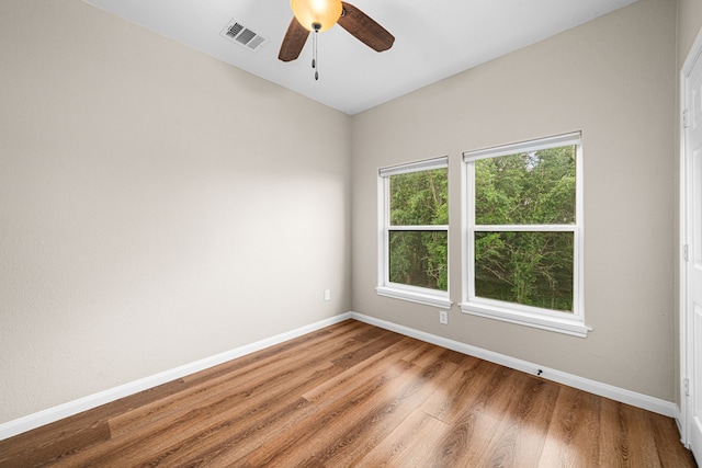 empty room with baseboards, wood finished floors, visible vents, and a ceiling fan