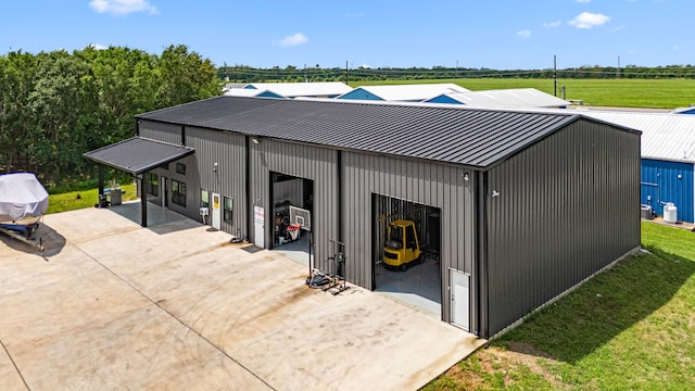 exterior space with a standing seam roof, driveway, metal roof, a pole building, and an outdoor structure