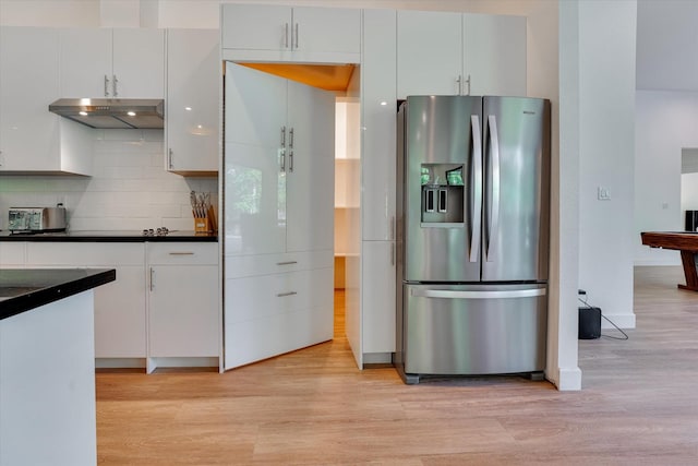 11571 Robin Ln, Conroe, TX 77303 - kitchen featuring stainless steel fridge, light wood-type flooring, dark countertops, backsplash, and under cabinet range hood