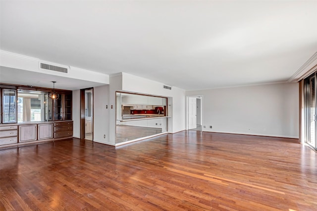 unfurnished living room with baseboards, wood finished floors, and visible vents