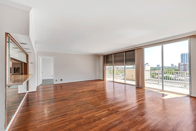 unfurnished living room with baseboards, wood finished floors, floor to ceiling windows, and crown molding