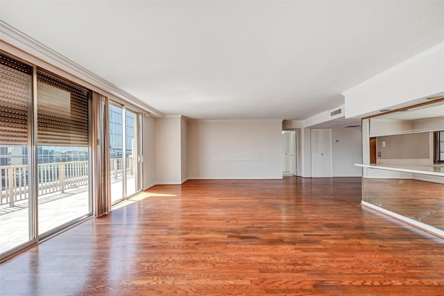 unfurnished living room featuring baseboards, wood finished floors, visible vents, and ornamental molding
