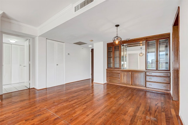 unfurnished living room with baseboards, dark wood-style flooring, crown molding, and visible vents