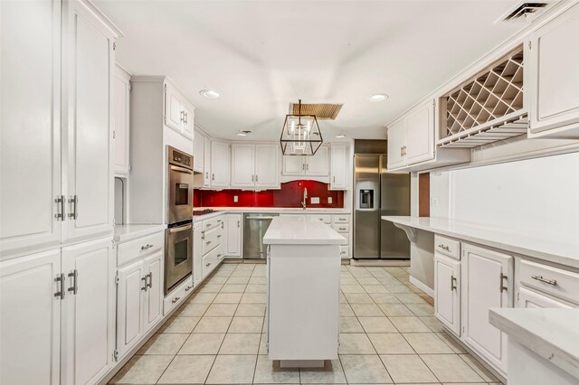 kitchen featuring white cabinets, stainless steel appliances, light countertops, visible vents, and a center island