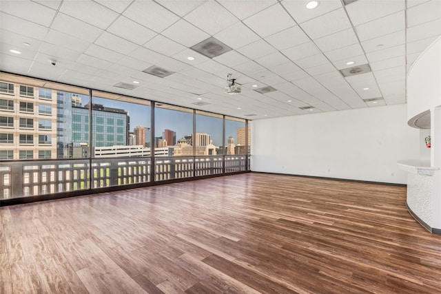 unfurnished room with visible vents, a city view, baseboards, and wood finished floors