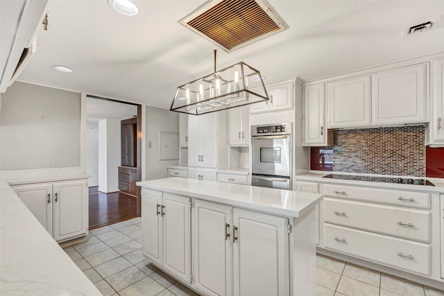 kitchen with light tile patterned flooring, cooktop, visible vents, and white cabinets