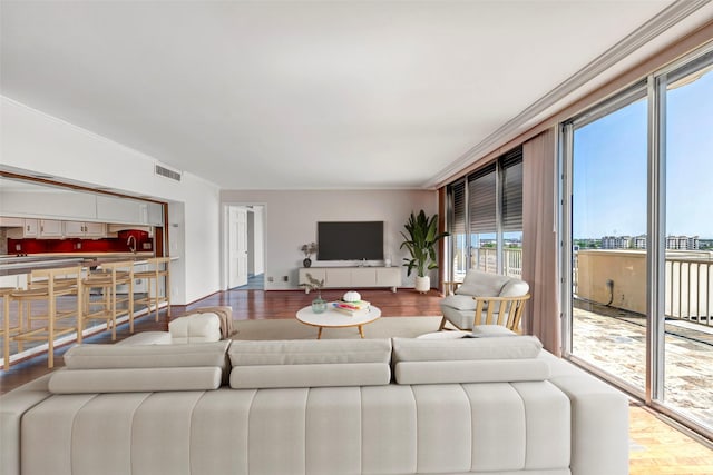 living room with baseboards, ornamental molding, wood finished floors, and visible vents