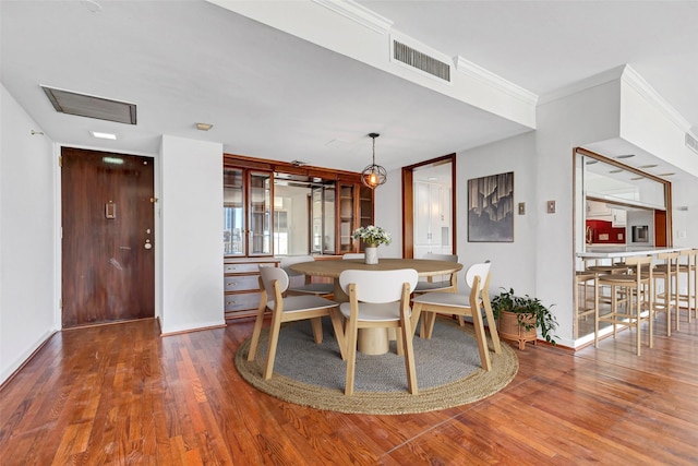 dining room with baseboards, ornamental molding, wood finished floors, and visible vents