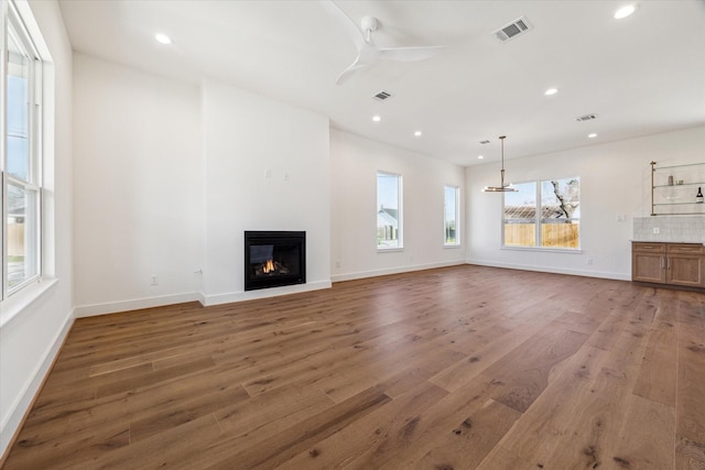 unfurnished living room with ceiling fan, wood finished floors, recessed lighting, a glass covered fireplace, and baseboards