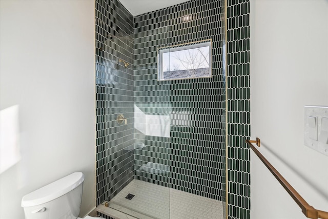 bathroom featuring tiled shower and toilet