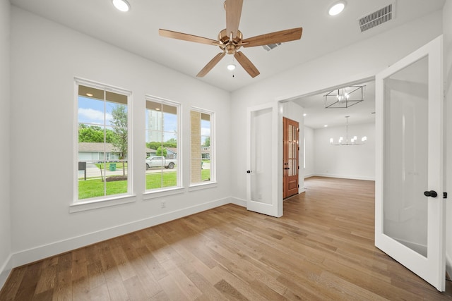 unfurnished room with visible vents, baseboards, recessed lighting, light wood-type flooring, and ceiling fan with notable chandelier