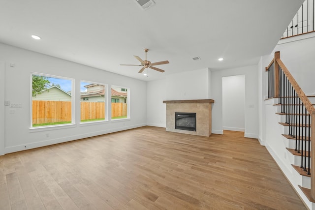 unfurnished living room featuring visible vents, stairs, ceiling fan, and light wood-type flooring