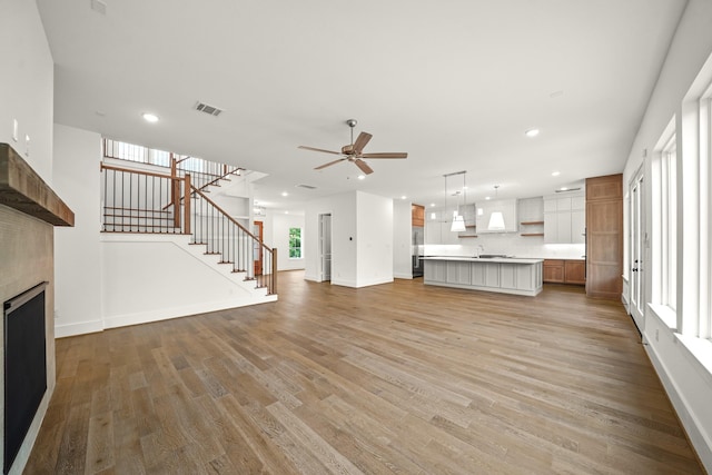 unfurnished living room featuring a ceiling fan, baseboards, visible vents, and light wood-style flooring