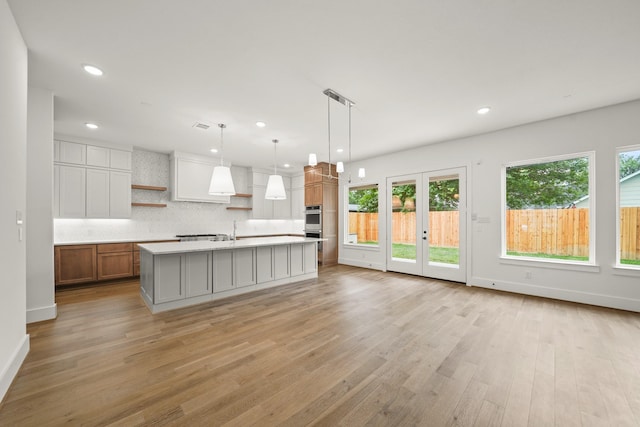 kitchen featuring open shelves, light wood finished floors, a healthy amount of sunlight, and light countertops