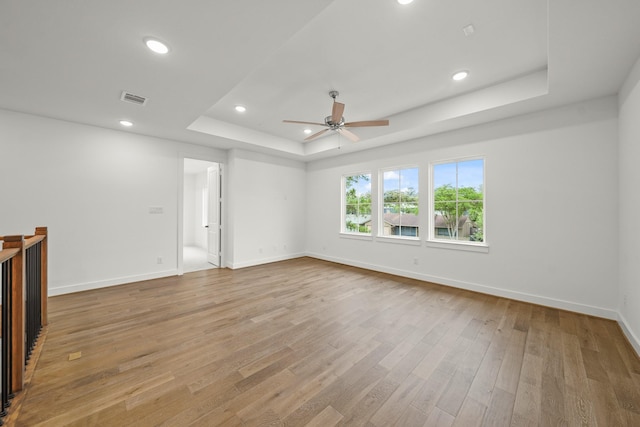 unfurnished room featuring light wood finished floors, a raised ceiling, a ceiling fan, baseboards, and recessed lighting