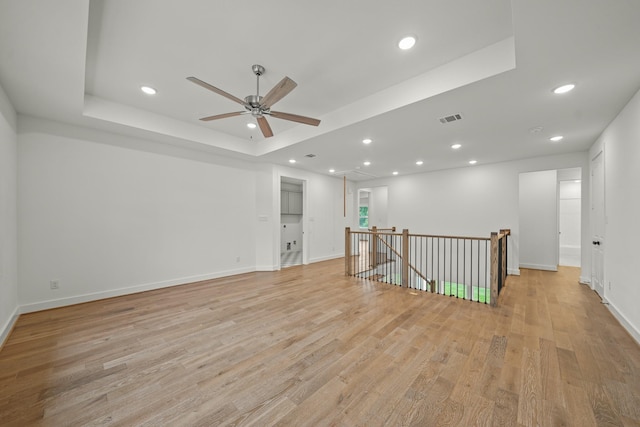 unfurnished room featuring ceiling fan, visible vents, light wood-type flooring, a raised ceiling, and recessed lighting