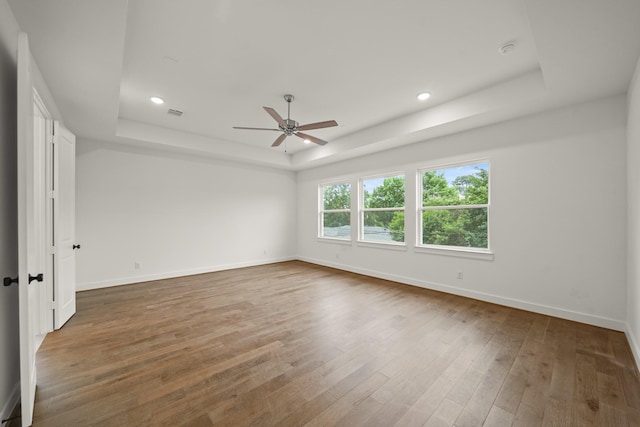 spare room featuring baseboards, a raised ceiling, ceiling fan, and wood finished floors