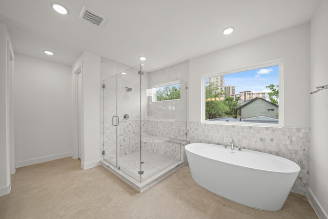 full bath featuring tile walls, visible vents, a freestanding bath, and a stall shower