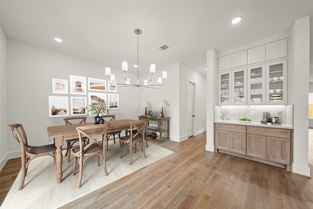 dining area with visible vents, light wood finished floors, and baseboards