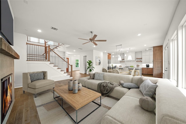 living room with light wood-style floors, recessed lighting, stairs, and visible vents