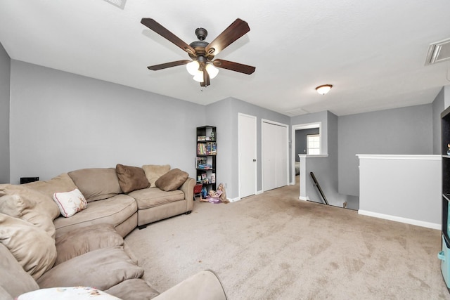 living area featuring attic access, baseboards, a ceiling fan, and carpet flooring