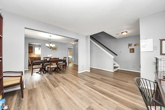 living room featuring light wood-style floors, stairway, baseboards, and a notable chandelier