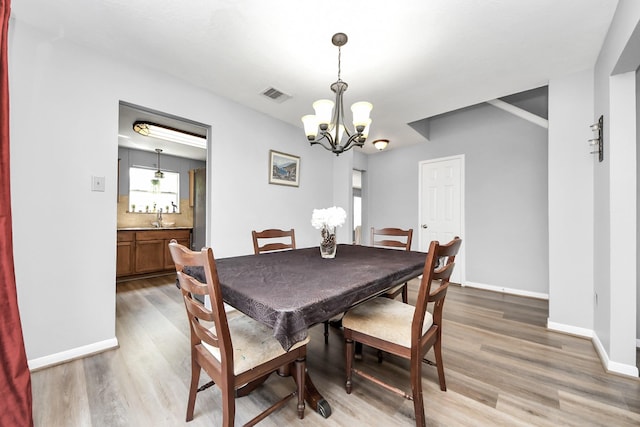 dining area featuring light wood-type flooring, baseboards, visible vents, and an inviting chandelier
