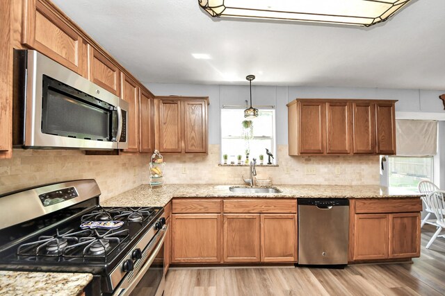 kitchen with light wood-style floors, decorative backsplash, stainless steel appliances, and a sink