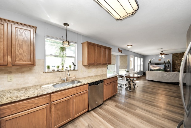 kitchen featuring stainless steel appliances, a sink, brown cabinets, and ceiling fan