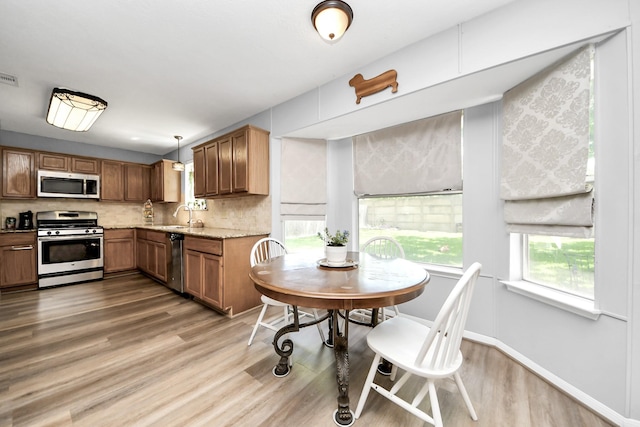 kitchen with stainless steel appliances, visible vents, a sink, light wood-style floors, and tasteful backsplash