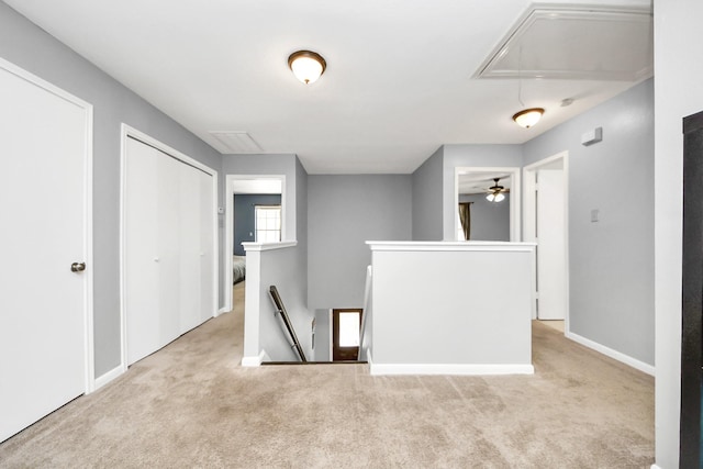 carpeted spare room featuring attic access and baseboards