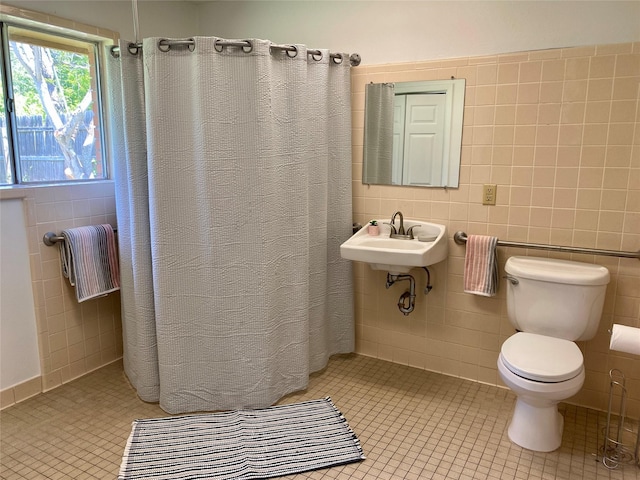 full bath featuring tile patterned floors, toilet, a sink, tile walls, and a shower with shower curtain