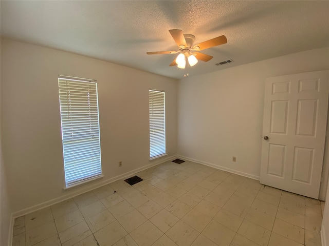 unfurnished room with ceiling fan, baseboards, a textured ceiling, and visible vents