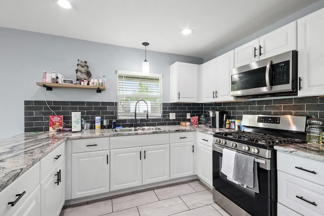 kitchen with white cabinets, a sink, light stone countertops, decorative backsplash, and appliances with stainless steel finishes