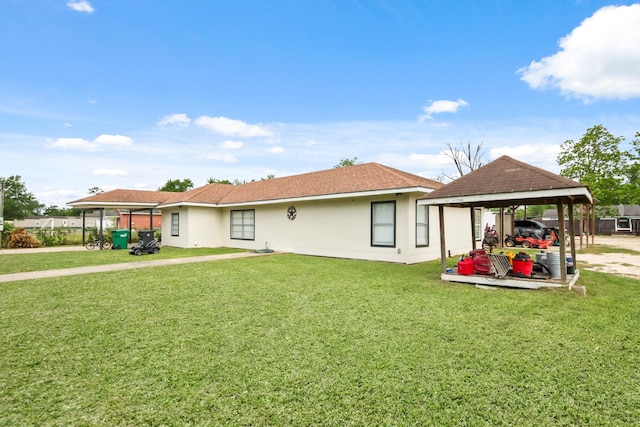rear view of property with stucco siding, a gazebo, and a yard