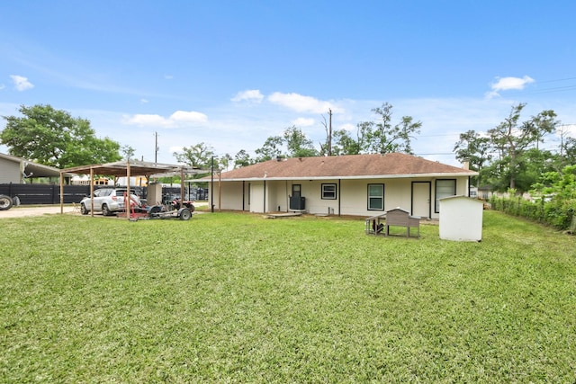 back of house featuring a detached carport, a lawn, and fence