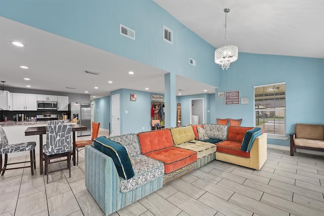 living room with visible vents, high vaulted ceiling, and an inviting chandelier