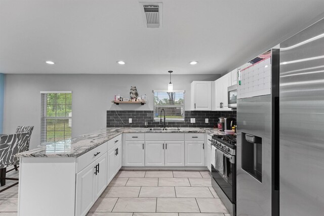 kitchen featuring a sink, a wealth of natural light, stainless steel appliances, a peninsula, and visible vents