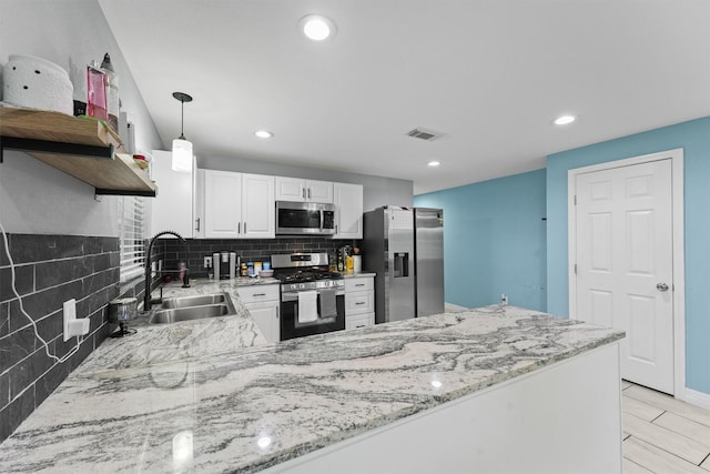kitchen featuring a sink, stainless steel appliances, backsplash, a peninsula, and visible vents