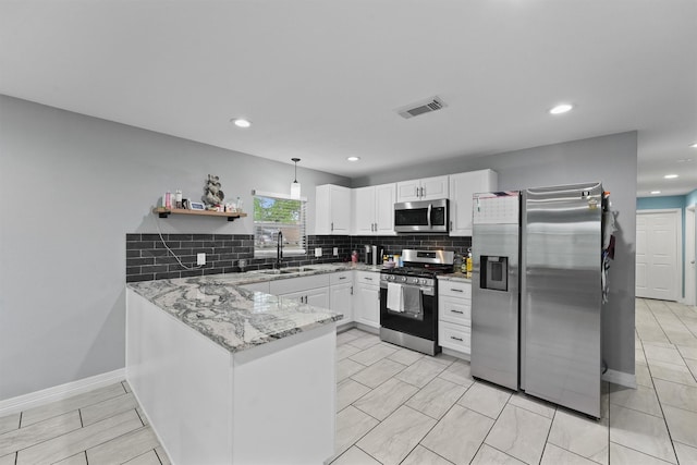 kitchen with white cabinets, stainless steel appliances, a peninsula, a sink, and tasteful backsplash