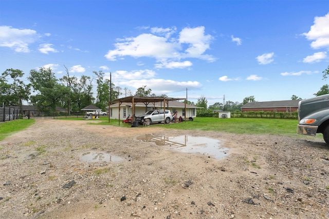 view of yard with a carport, driveway, and fence