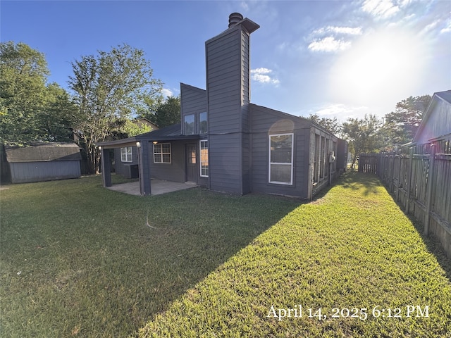 rear view of property with a lawn, fence, a patio area, and a shed