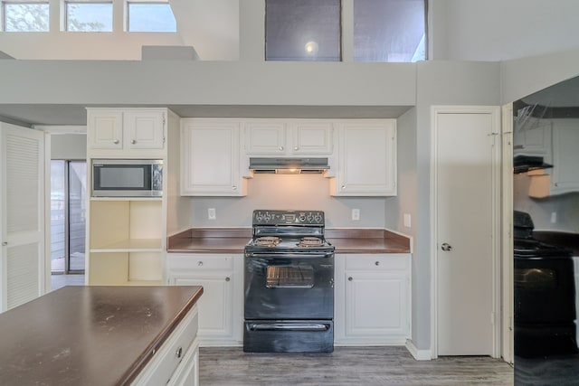 8810 Enchanted Forest Dr, Houston, TX 77088 - kitchen with dark countertops, range, stainless steel microwave, black / electric stove, and light wood-type flooring