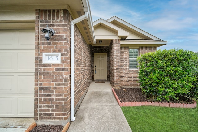 view of exterior entry featuring brick siding and a garage