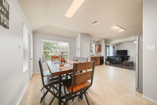 dining room with light floors, vaulted ceiling, visible vents, and baseboards