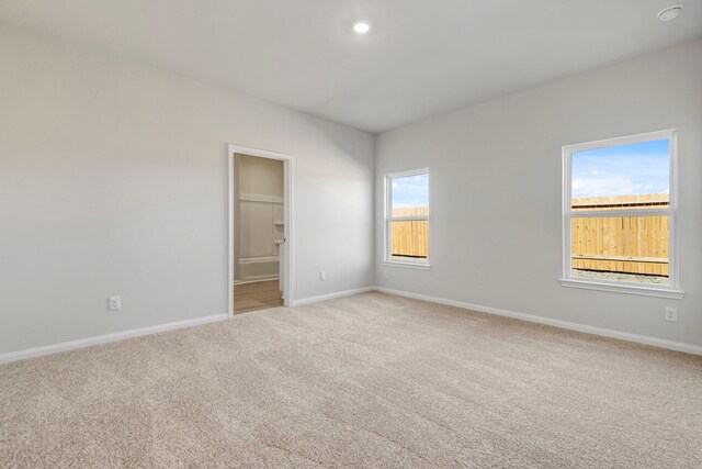spare room featuring light colored carpet, recessed lighting, and baseboards